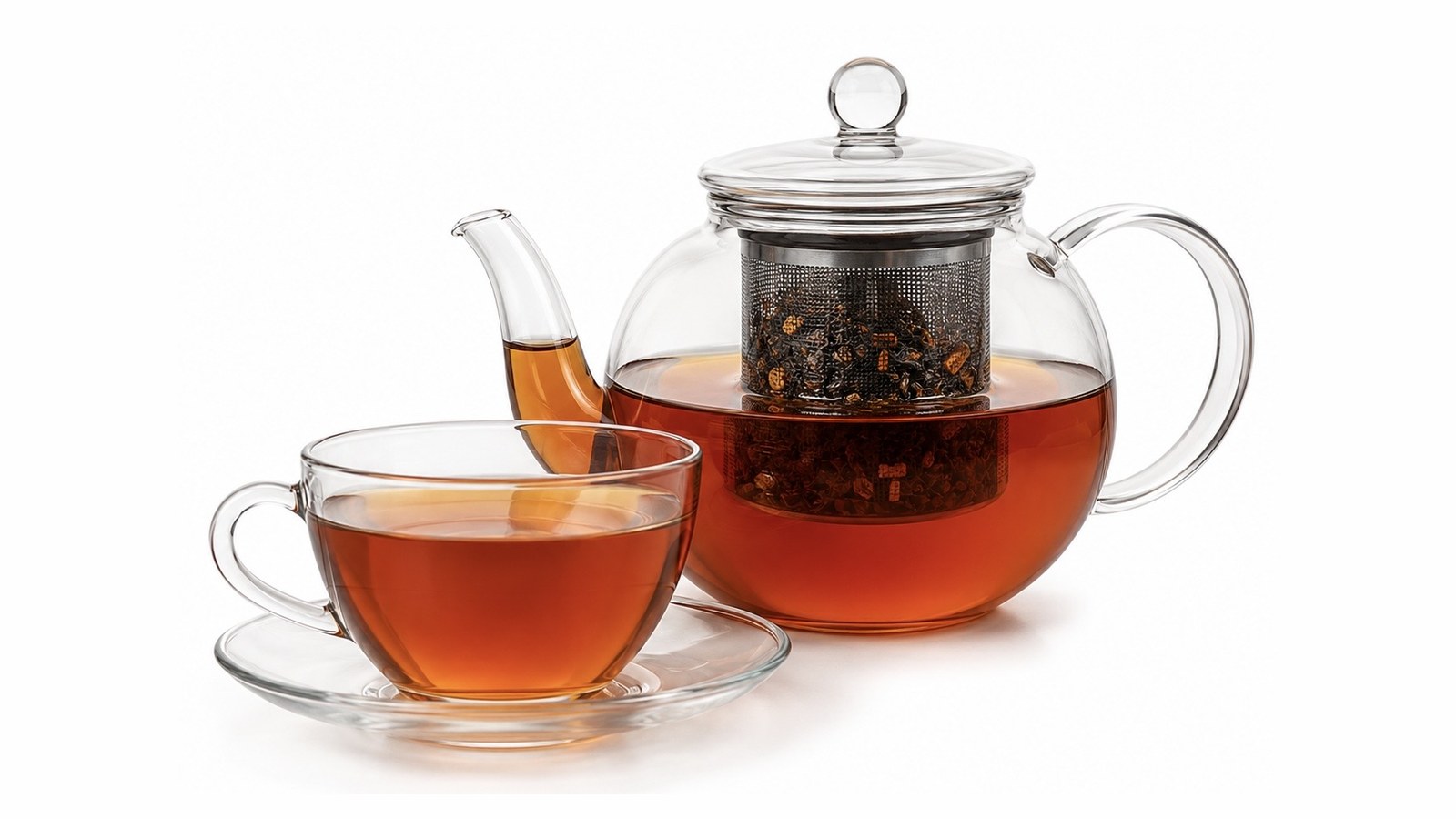 Glass teapot with an infuser basket of loose leaf beside a filled glass cup and saucer